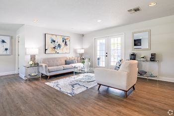A living room with a white couch and a blue rug.